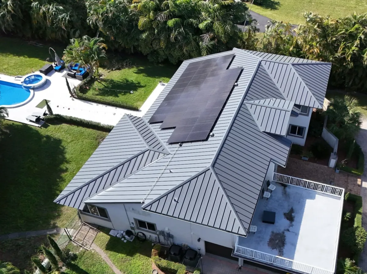 Solar panels installed on a standing seam metal roof with pool and palms